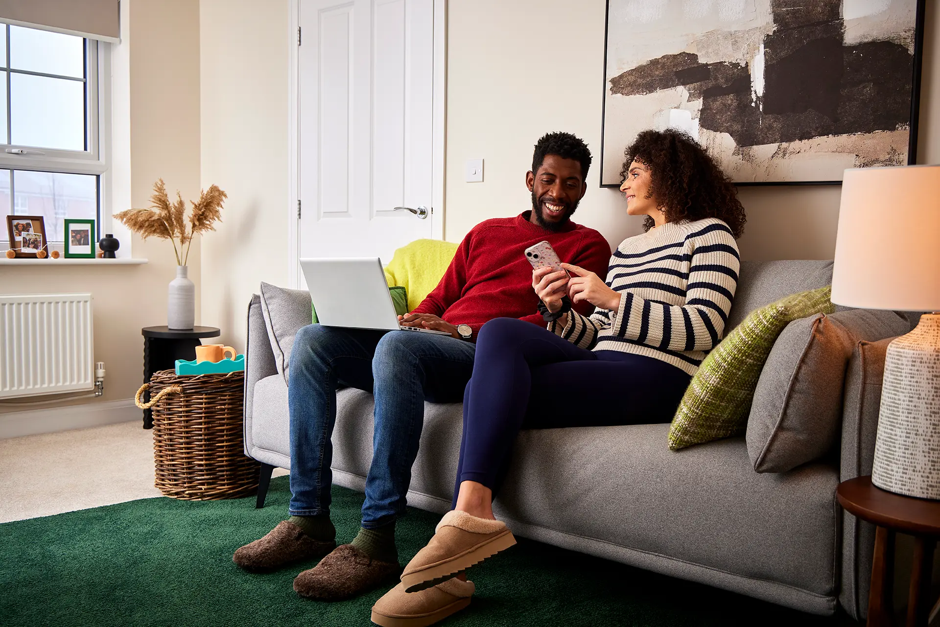 A man and a woman sitting on a couch, the woman showing the man something on her phone