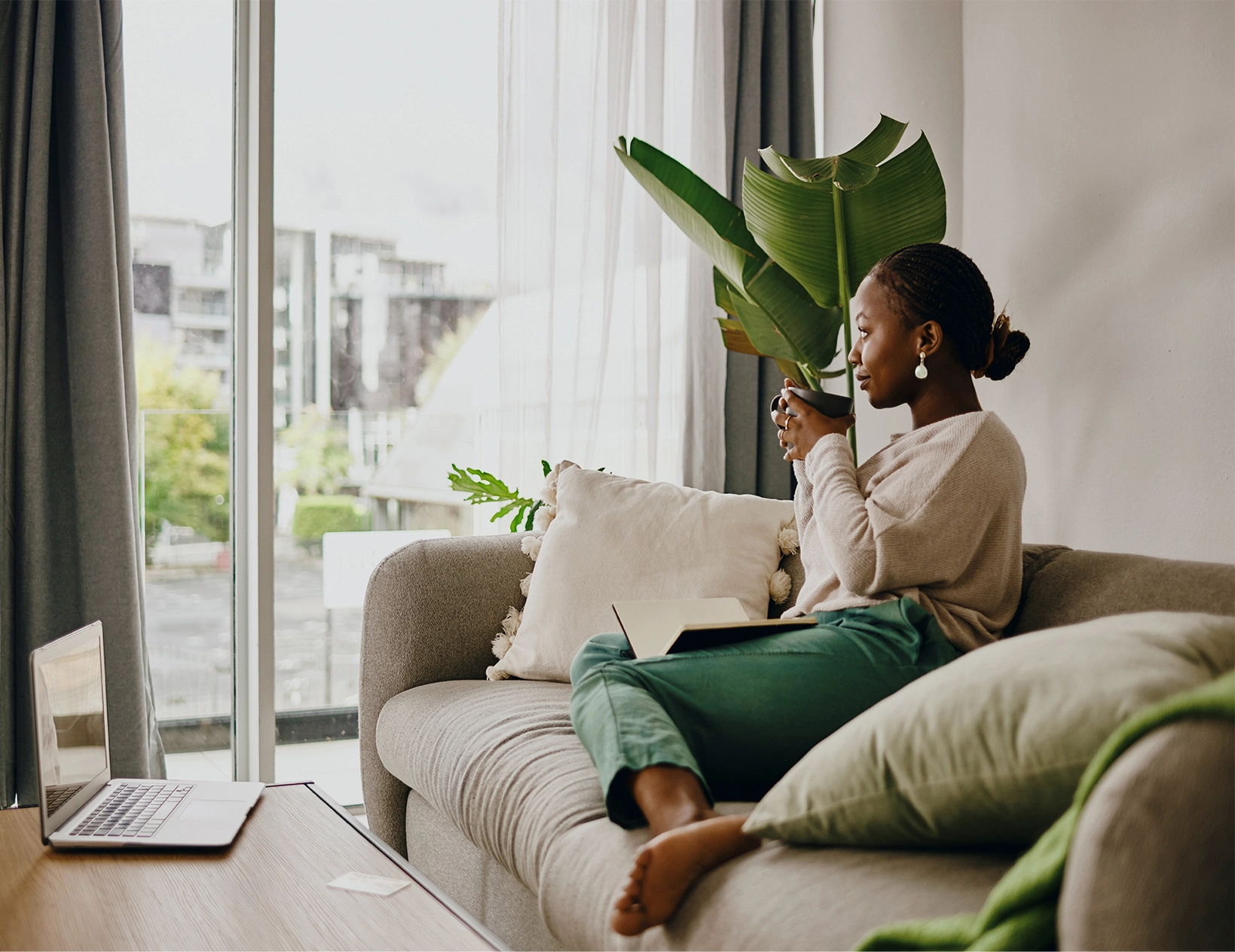 Woman sat on sofa drinking cup of tea